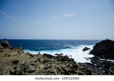 Waves Collide Against A Black Rock Formation.