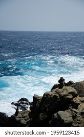 Waves Collide Against A Black Rock Formation.