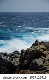 Waves Collide Against A Black Rock Formation.