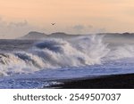 Waves crash against the Norfolk at high tide on a crisp cold morning in the winter in England