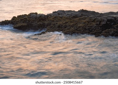 Waves crash against rocks covered in moss and seaweed on the shore. The image was taken using a slow shutter speed with a silky water effect. beautiful nature concept. - Powered by Shutterstock