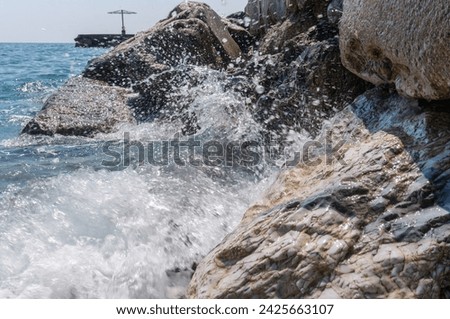 Waves crash against a stone pier with a walkway.