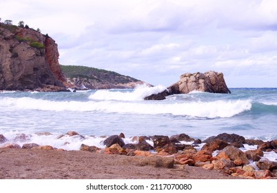 Waves Crash On Rocks. Solid As A Rock. Cloudy Blue Sky. Rough Water With Waves .Rock Solid.