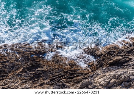 Waves crash and splash on rocks, aerial view from the top