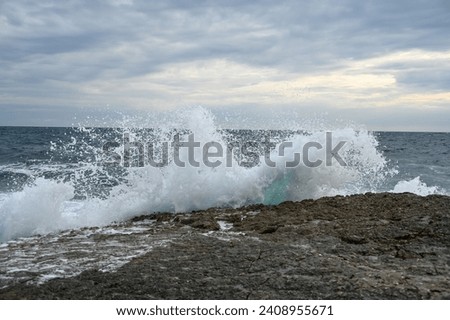 Waves crashing into rocks on the sea. Waves breaking on the shore. High cliffs by the sea. Rocky coastline.  