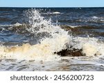 Waves crashing off huge boulders in the water near the shore of the beach on the North Fork of Long Island, NY