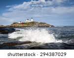 Waves crashing on rocks by lighthouse in Maine. Reflection of waves appear in cloud formations above the beacon.