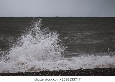 Waves Crashing on Rocky Shoreline in Overcast Weather
 Dynamic shot of ocean waves crashing against a rocky shoreline, with an overcast sky adding a moody, dramatic atmosphere.
 - Powered by Shutterstock