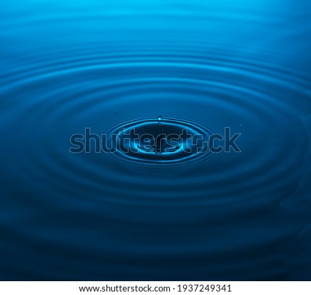 waves from a falling drop into blue water. copy space