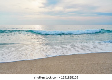                                Waves with foam hitting sand on a tropical sandy beach during sunset. Sea scape. Natural background.