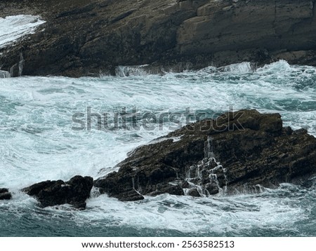 waves hitting rocks at the bottom of a cliff