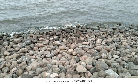 Waves lapping at the rocky shore. Autumn day, Clear water waves run over the rocky steep coast. There are many large stones with rounded edges on the shore.
