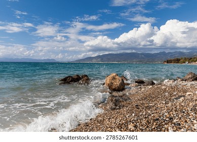 Waves on pebble beach with dramatic clouds and mountains near Avia Kalamata Greece