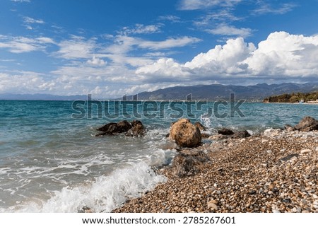 Waves on pebble beach with dramatic clouds and mountains near Avia Kalamata Greece