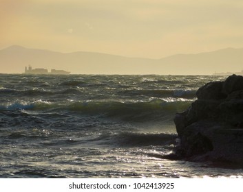 Waves On A Rough Sea And A Container Ship, Near Sunset, From The Shore Of Glyfada, Greece