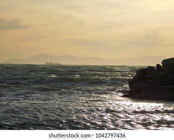 Waves On A Rough Sea And A Container Ship, Near Sunset, From The Shore Of Glyfada, Greece