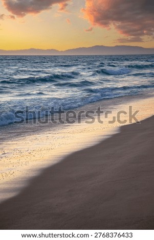 Waves on a sandy ocean beach under a beautiful sunset sky with clouds in Santa Monica. LA. USA.
