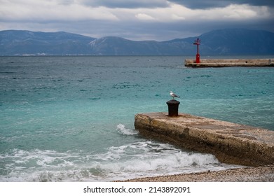 Waves on the sea at cloudy winter day. Gradac, Croatia. Lighthouse and dock. Adriatic Sea at cloudy day. Seagull.