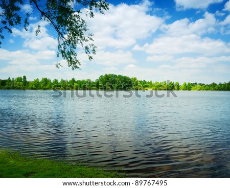 waves on water of lake and green trees on sky background