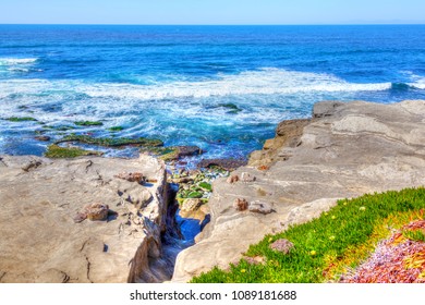 Waves from the Pacific Ocean pound against the rocky cliffs of La Jolla beach in San Diego, California. The scenic coastline is a popular attraction in Southern California.