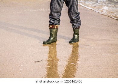 Waves rolling in on a sandy beach and washing off footprints in the sand.