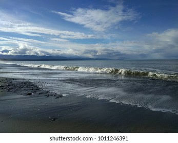 waves rolling in under a cloudy blue sky
