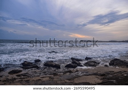 As waves softly touch the rocks, the evening sea radiates peace and calm, revealing nature’s quiet beauty at the horizon.