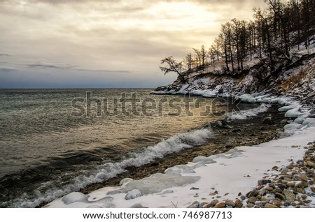 Waves and splash on Lake Baikal with rocks and trees in Uzuri bay in sunset. Russia, Siberia