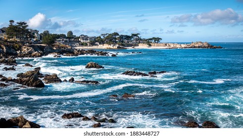 Waves splash on the rocky coast along the Monterey Bay, in Pacific Grove, California,  on a windy winter day.  Lover's point is seen in the background.