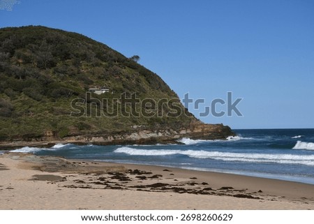 The waves splashing and bouncing on the sandy Australian beach against the clear blue sky