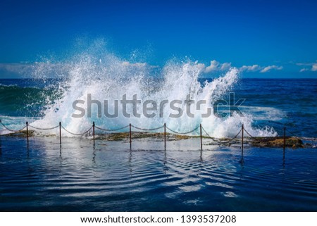 Waves splashing over rocks at Bogey Hole swimming pool in Newcastle Australia