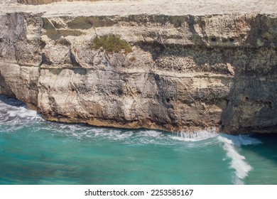 Waves of turquoise water breaking at the foot of a cliff. Rocky limestone beach in Torre dell'Orso, Italy. - Shutterstock ID 2253585167