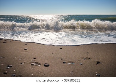 Waves Wash Over Dark Sand On The Beach