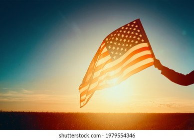 Waving American Flag Outdoors. Hand Holds Usa National Flag At Sunset. 4th July Independence Day