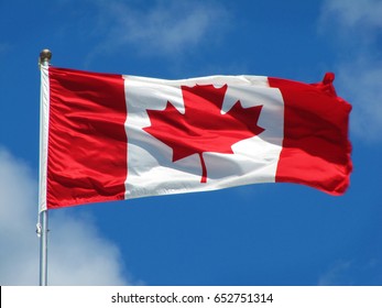 Waving Canadian Flag Against The Blue Sky