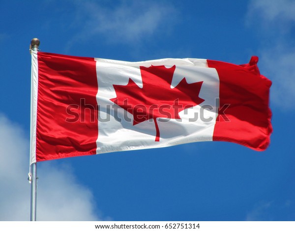 Waving Canadian flag\
against the blue sky