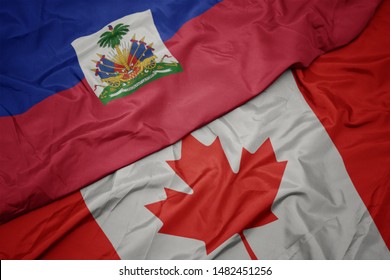 waving colorful flag of canada and national flag of haiti. macro