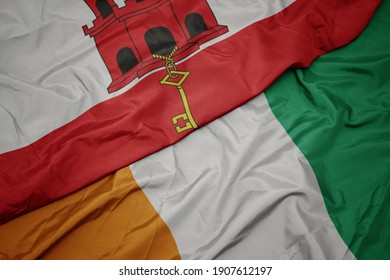 waving colorful flag of cote divoire and national flag of gibraltar. macro