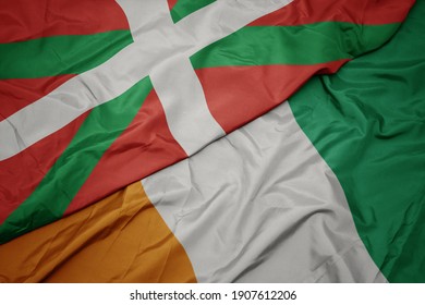 waving colorful flag of cote divoire and national flag of basque country. macro