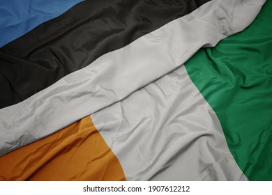waving colorful flag of cote divoire and national flag of estonia. macro