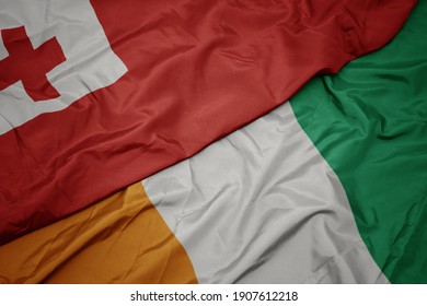 waving colorful flag of cote divoire and national flag of Tonga . macro