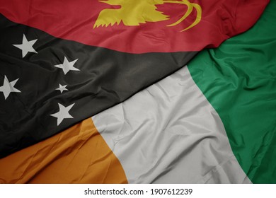 waving colorful flag of cote divoire and national flag of Papua New Guinea . macro