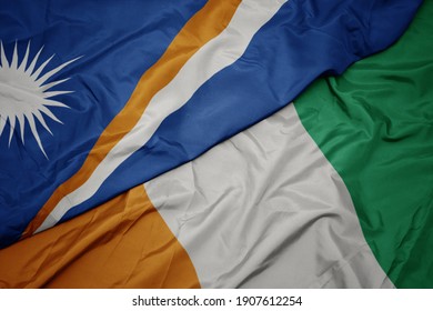 waving colorful flag of cote divoire and national flag of Marshall Islands . macro