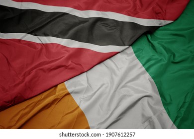 waving colorful flag of cote divoire and national flag of trinidad and tobago. macro