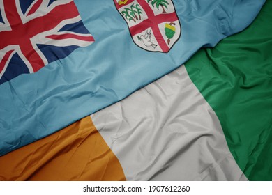 waving colorful flag of cote divoire and national flag of Fiji . macro