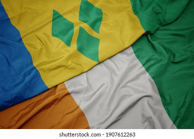 waving colorful flag of cote divoire and national flag of saint vincent and the grenadines. macro