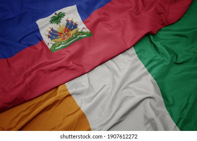 waving colorful flag of cote divoire and national flag of haiti. macro