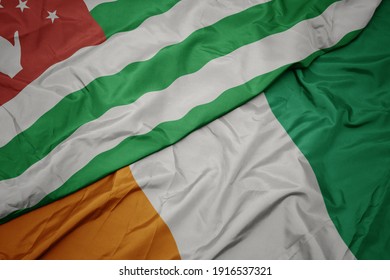 waving colorful flag of cote divoire and national flag of abkhazia. macro