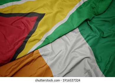 waving colorful flag of cote divoire and national flag of guyana. macro