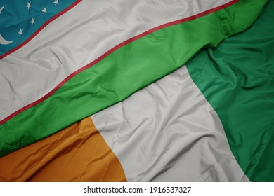 waving colorful flag of cote divoire and national flag of uzbekistan. macro